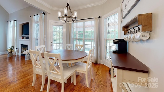 3005 Monterrey Ln, Monroe, NC 28110 - dining area featuring a chandelier, light wood-type flooring, crown molding, and a glass covered fireplace