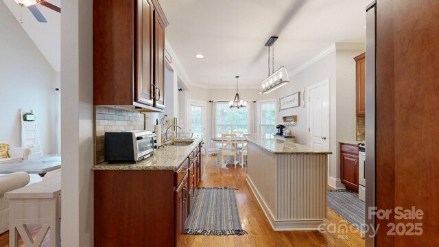 3005 Monterrey Ln, Monroe, NC 28110 - kitchen featuring light wood-style floors, tasteful backsplash, light stone counters, a kitchen island, and crown molding