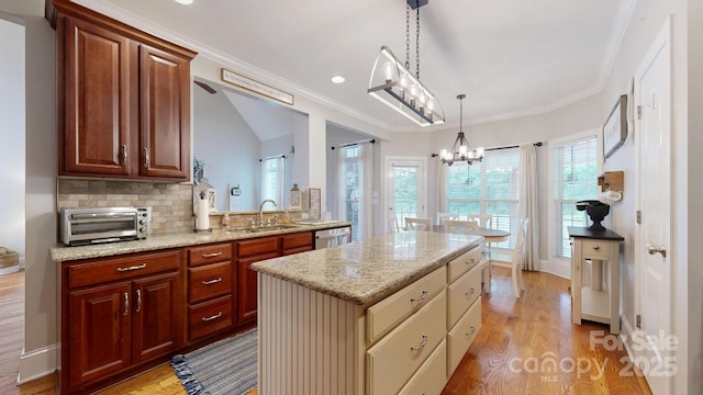 3005 Monterrey Ln, Monroe, NC 28110 - kitchen with light wood-style floors, light stone counters, a chandelier, a center island, and ornamental molding