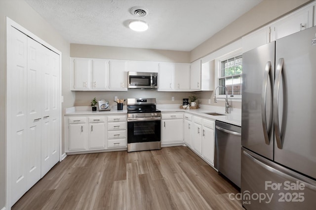 1409 Kensington Rd Unit B-8, Hendersonville, NC 28791 - kitchen with stainless steel appliances, light wood-style floors, light countertops, white cabinetry, and a textured ceiling
