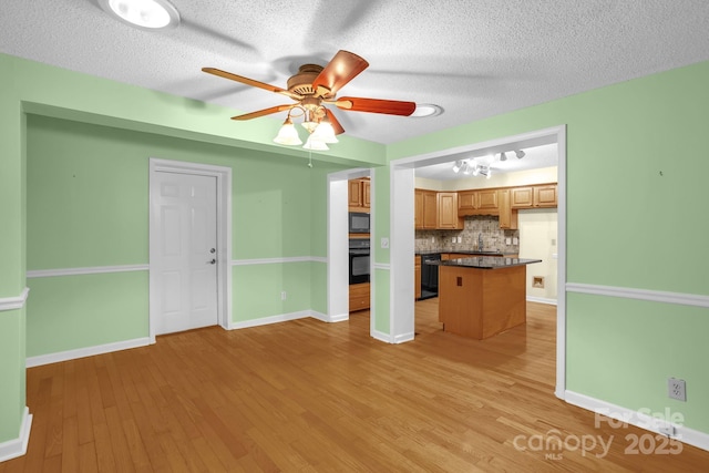 106 Birmingham Pl, Salisbury, NC 28146 - kitchen with black appliances, dark countertops, tasteful backsplash, a ceiling fan, and light wood-style flooring