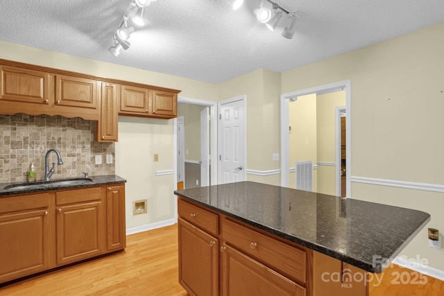 106 Birmingham Pl, Salisbury, NC 28146 - kitchen featuring track lighting, light wood-style flooring, backsplash, brown cabinets, and a textured ceiling