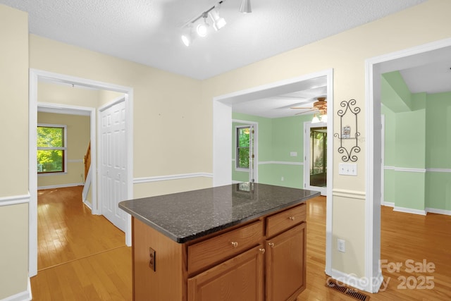 106 Birmingham Pl, Salisbury, NC 28146 - kitchen with light wood-type flooring, ceiling fan, dark stone countertops, a kitchen island, and rail lighting