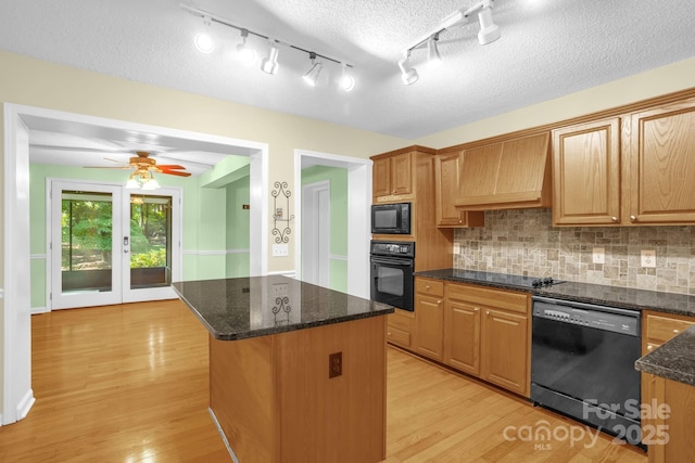 106 Birmingham Pl, Salisbury, NC 28146 - kitchen with black appliances, custom exhaust hood, a center island, light wood-style flooring, and decorative backsplash