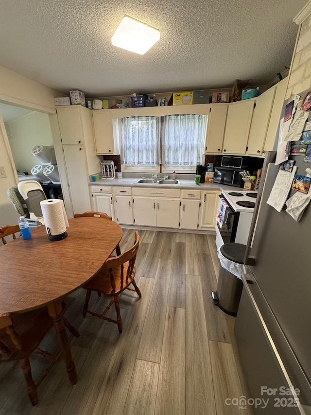 1045 Warren Pl NW, Lenoir, NC 28645 - kitchen featuring freestanding refrigerator, white electric range, a textured ceiling, light wood-style floors, and light countertops