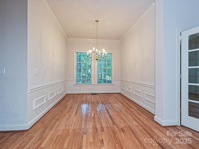 10638 Moss Mill Ln, Charlotte, NC 28277 - unfurnished dining area featuring a chandelier, light wood-style floors, crown molding, a wainscoted wall, and a decorative wall