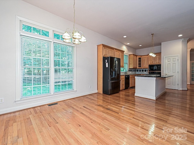 10638 Moss Mill Ln, Charlotte, NC 28277 - kitchen with black appliances, light wood-style floors, dark countertops, a chandelier, and backsplash