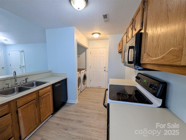 4002 Beaverbrook Dr, Indian Trail, NC 28079 - kitchen with washer and clothes dryer, brown cabinets, black appliances, a textured ceiling, and light wood finished floors