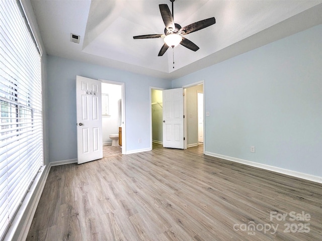 4002 Beaverbrook Dr, Indian Trail, NC 28079 - unfurnished bedroom with a tray ceiling, wood finished floors, multiple windows, and connected bathroom