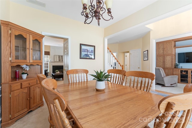 5630 Cambridge Bay Dr, Charlotte, NC 28269 - dining space with a chandelier, stairs, light carpet, and a fireplace