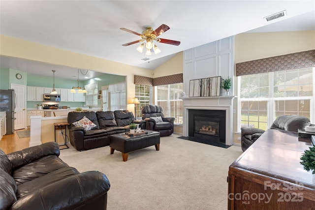 5630 Cambridge Bay Dr, Charlotte, NC 28269 - living room featuring lofted ceiling, a ceiling fan, a fireplace with flush hearth, and light colored carpet