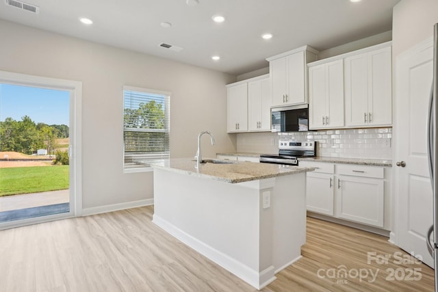 1997 Paddlewheel Dr, Stanley, NC 28164 - kitchen featuring stainless steel appliances, a kitchen island with sink, light wood-type flooring, backsplash, and light stone counters