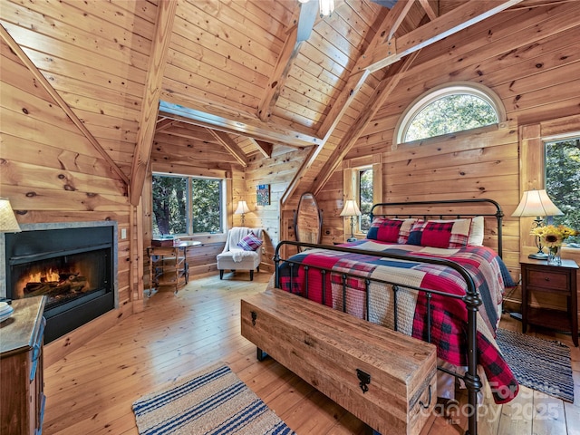 220 Circle Pines Dr, Rosman, NC 28772 - bedroom featuring wooden walls, hardwood / wood-style floors, a wood ceiling with exposed beams, a warm lit fireplace, and high vaulted ceiling
