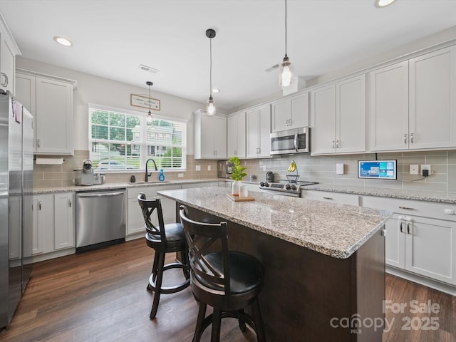 8810 Crape Myrtle Dr, Stanfield, NC 28163 - kitchen with appliances with stainless steel finishes, backsplash, a center island, a breakfast bar area, and dark wood-style floors