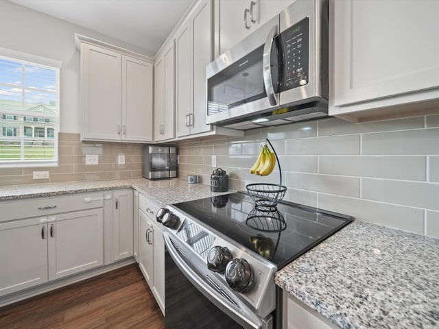 8810 Crape Myrtle Dr, Stanfield, NC 28163 - kitchen with stainless steel appliances, tasteful backsplash, light stone counters, dark wood-style floors, and white cabinetry