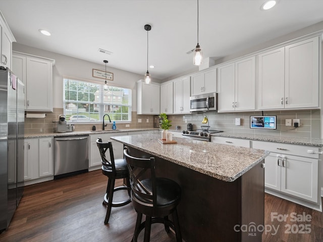 8810 Crape Myrtle Dr, Stanfield, NC 28163 - kitchen featuring stainless steel appliances, tasteful backsplash, a center island, white cabinetry, and a breakfast bar