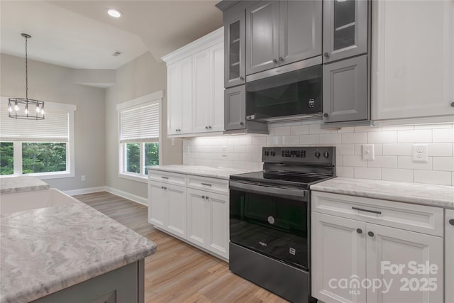 5005 Oconee Dr, Stanley, NC 28164 - kitchen with stainless steel appliances, light wood finished floors, backsplash, a chandelier, and glass insert cabinets