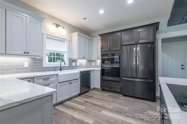 5009 Oconee Dr, Stanley, NC 28164 - kitchen featuring appliances with stainless steel finishes, tasteful backsplash, light stone counters, light wood-style floors, and recessed lighting