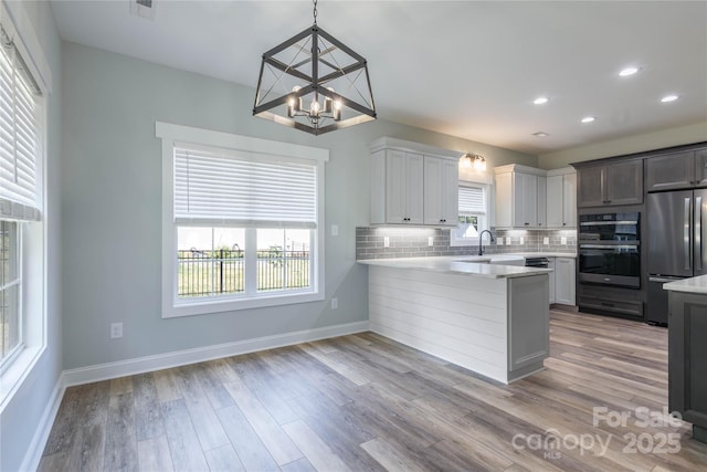 5009 Oconee Dr, Stanley, NC 28164 - kitchen with stainless steel refrigerator, a chandelier, light countertops, backsplash, and a peninsula
