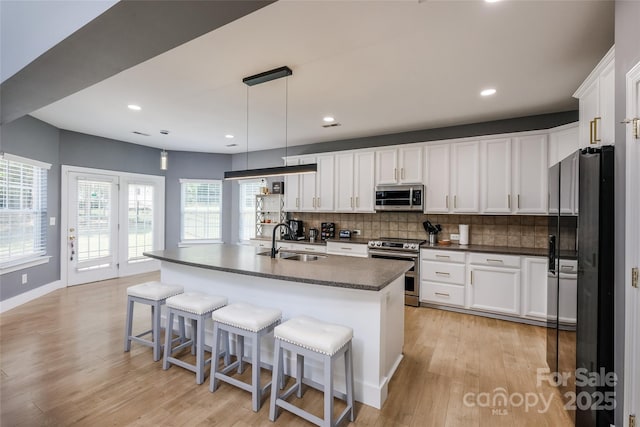 2002 Ledare Ln Unit 70, Indian Trail, NC 28079 - kitchen featuring stainless steel appliances, dark countertops, decorative backsplash, white cabinets, and light wood-style floors