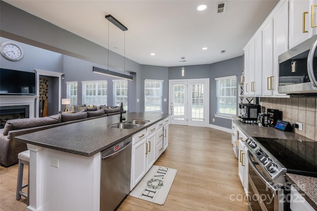 2002 Ledare Ln Unit 70, Indian Trail, NC 28079 - kitchen featuring appliances with stainless steel finishes, dark countertops, open floor plan, white cabinets, and an island with sink