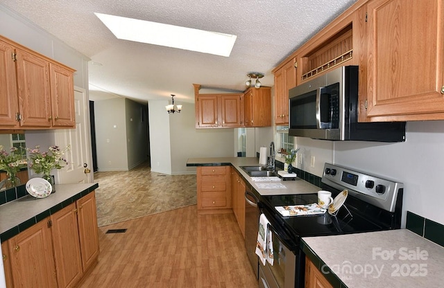 1924 Junction Rd, Mocksville, NC 27028 - kitchen featuring appliances with stainless steel finishes, a skylight, a peninsula, a textured ceiling, and a chandelier