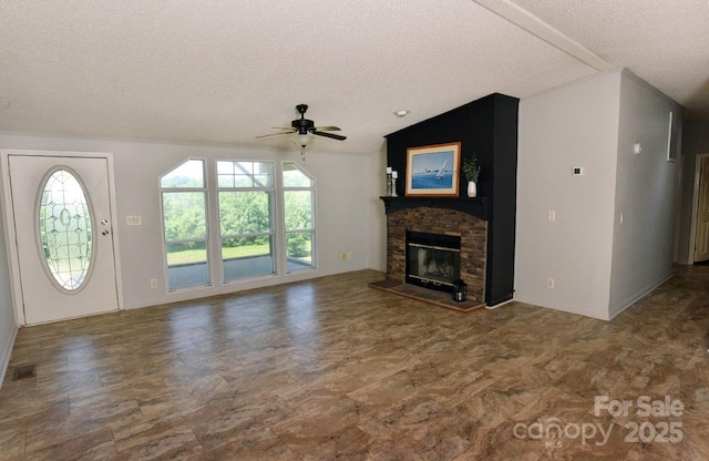 1924 Junction Rd, Mocksville, NC 27028 - unfurnished living room with a textured ceiling, a ceiling fan, plenty of natural light, a glass covered fireplace, and vaulted ceiling