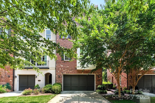 1614 Lombardy Cir, Charlotte, NC 28203 - view of front facade featuring concrete driveway, a balcony, an attached garage, and brick siding