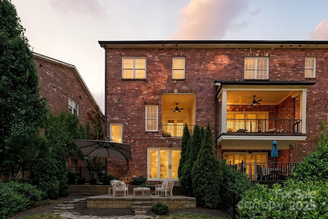 1614 Lombardy Cir, Charlotte, NC 28203 - back of house at dusk featuring a balcony, brick siding, and french doors