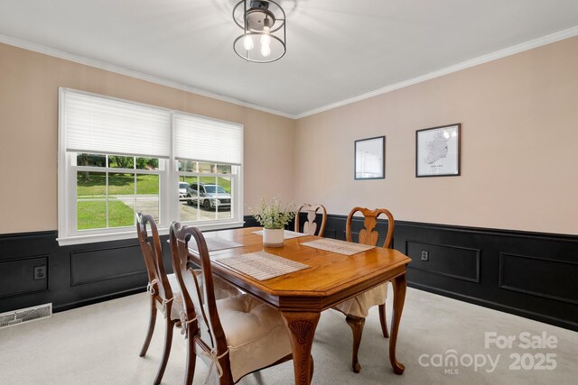586 Crestside Dr SE, Concord, NC 28025 - dining space with light carpet, ornamental molding, a wainscoted wall, and a decorative wall