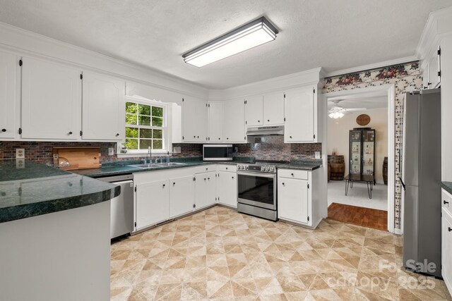 586 Crestside Dr SE, Concord, NC 28025 - kitchen with under cabinet range hood, appliances with stainless steel finishes, white cabinetry, backsplash, and crown molding