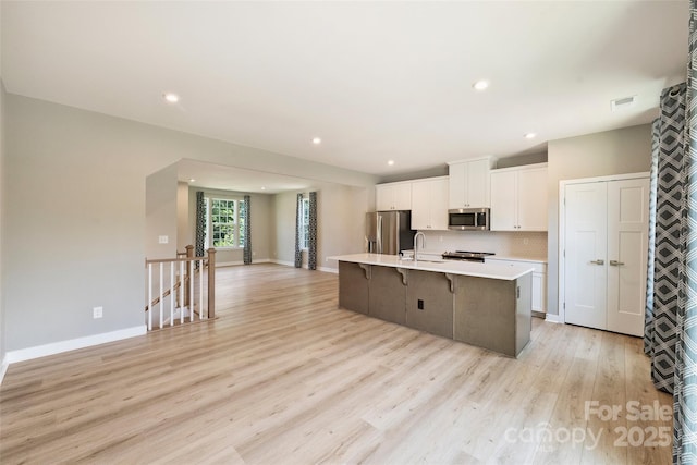 342 Cramerton Mills Parkway, Cramerton, NC 28032 - kitchen with stainless steel appliances, white cabinetry, light countertops, a kitchen island with sink, and a kitchen breakfast bar