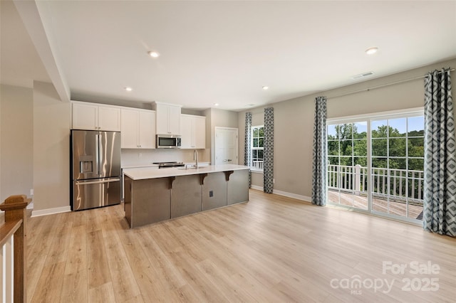 342 Cramerton Mills Parkway, Cramerton, NC 28032 - kitchen featuring appliances with stainless steel finishes, a kitchen island with sink, white cabinets, light wood-type flooring, and light countertops