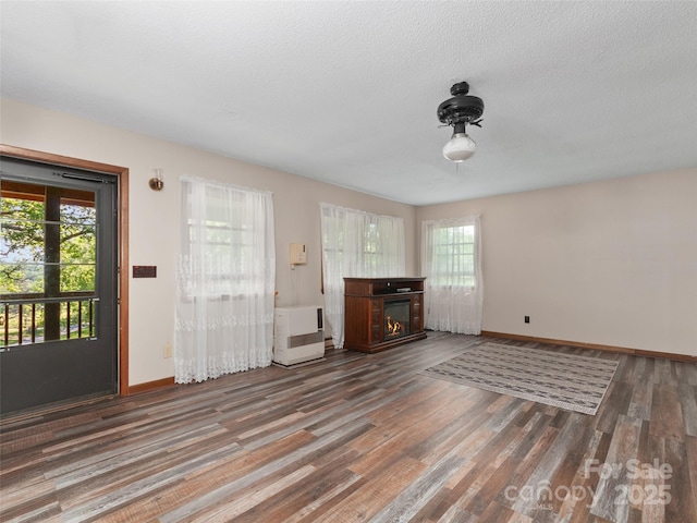 250 Turkey Pen Rd, Franklin, NC 28734 - unfurnished living room featuring plenty of natural light, a glass covered fireplace, wood finished floors, and heating unit