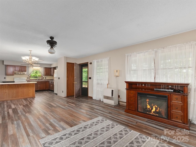 250 Turkey Pen Rd, Franklin, NC 28734 - unfurnished living room featuring a chandelier, dark wood-style flooring, a glass covered fireplace, heating unit, and a textured ceiling
