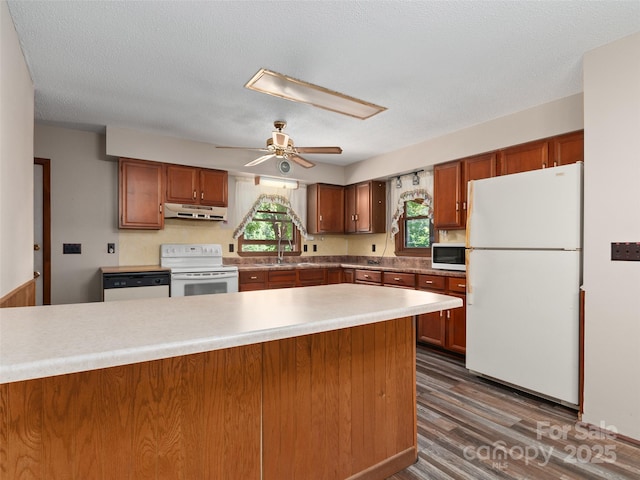 250 Turkey Pen Rd, Franklin, NC 28734 - kitchen with white appliances, under cabinet range hood, light countertops, dark wood-type flooring, and brown cabinetry
