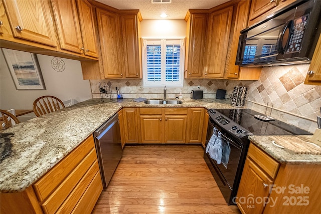 696 Springwood Dr, Mount Gilead, NC 27306 - kitchen featuring black appliances, light wood finished floors, light stone countertops, brown cabinetry, and a textured ceiling