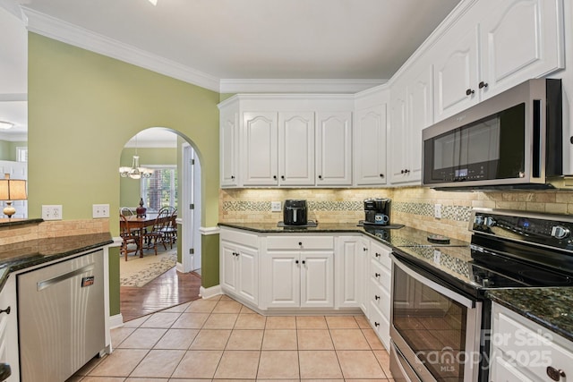 3865 Willow Grove Ln, Concord, NC 28025 - kitchen featuring stainless steel appliances, arched walkways, light tile patterned floors, white cabinetry, and decorative backsplash