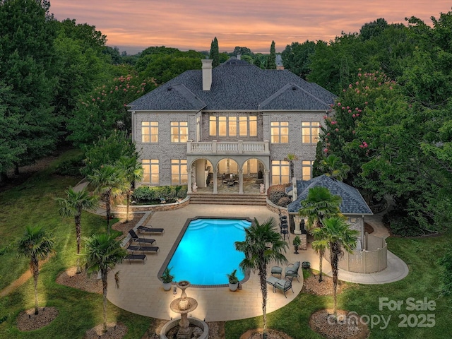18201 Mainsail Pointe Dr, Cornelius, NC 28031 - rear view of property with a balcony, a patio, an outdoor pool, a chimney, and a shingled roof