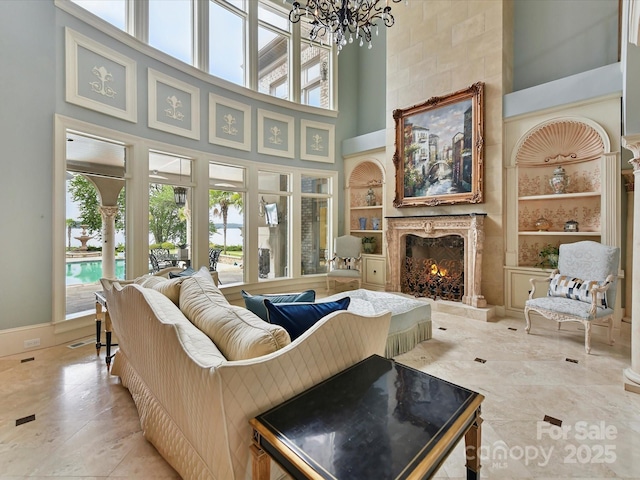 18201 Mainsail Pointe Dr, Cornelius, NC 28031 - living room featuring built in shelves, a towering ceiling, plenty of natural light, a premium fireplace, and a chandelier