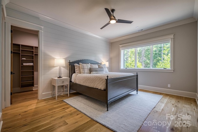 256 Hunt Camp Dr, Nebo, NC 28761 - bedroom featuring a walk in closet, crown molding, light wood finished floors, wooden walls, and ceiling fan