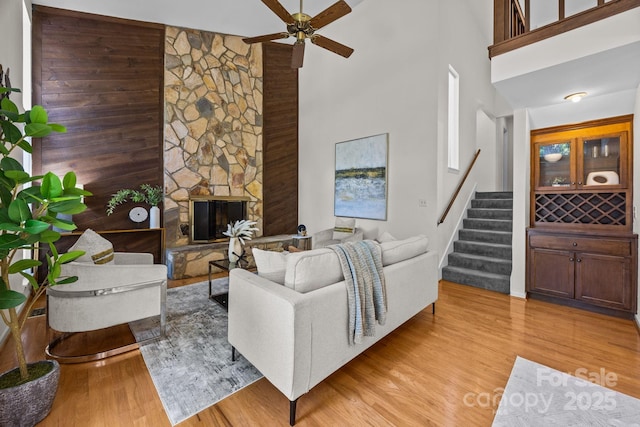 9008 St Croix Ln, Charlotte, NC 28277 - living room with ceiling fan, stairway, a towering ceiling, light wood finished floors, and a stone fireplace