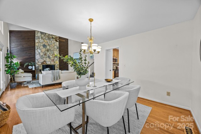 9008 St Croix Ln, Charlotte, NC 28277 - dining room featuring a fireplace, light wood-type flooring, a chandelier, and ceiling fan