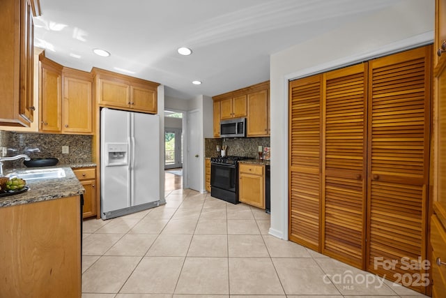 9008 St Croix Ln, Charlotte, NC 28277 - kitchen featuring white fridge with ice dispenser, black range with gas cooktop, stainless steel microwave, decorative backsplash, and light tile patterned floors