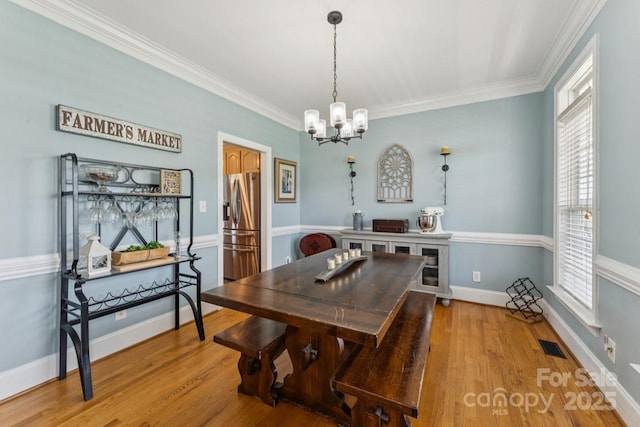 1123 Snyders Store Rd, Wingate, NC 28174 - dining space with a chandelier, healthy amount of natural light, light wood-type flooring, and crown molding