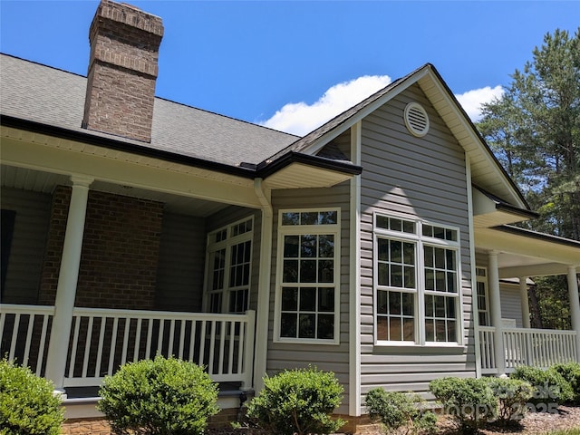 6301 Hawk Nest Dr, Concord, NC 28027 - view of side of home with a porch, a chimney, a shingled roof, and brick siding