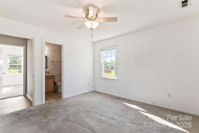 600 Piper Ct, Wingate, NC 28174 - unfurnished bedroom with multiple windows, carpet floors, ensuite bath, and a ceiling fan