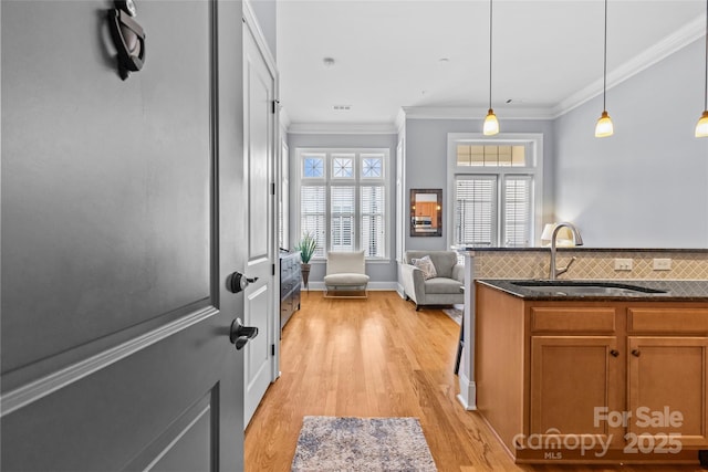 2810 Selwyn Ave Unit 429, Charlotte, NC 28209 - kitchen featuring light wood finished floors, brown cabinetry, hanging light fixtures, crown molding, and backsplash