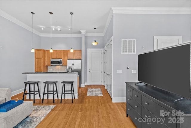 2810 Selwyn Ave Unit 429, Charlotte, NC 28209 - kitchen with stainless steel appliances, dark countertops, crown molding, light wood finished floors, and decorative light fixtures
