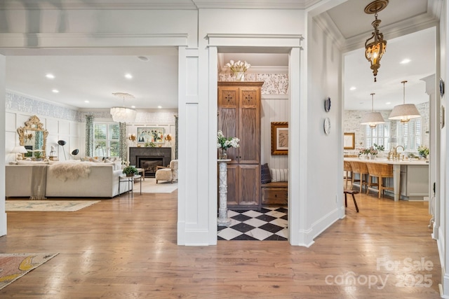 3519 Mcpherson St, Waxhaw, NC 28173 - foyer entrance featuring crown molding, wood finished floors, a glass covered fireplace, wallpapered walls, and a chandelier